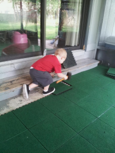 Child with a mallet installing Coverdeck deck tiles